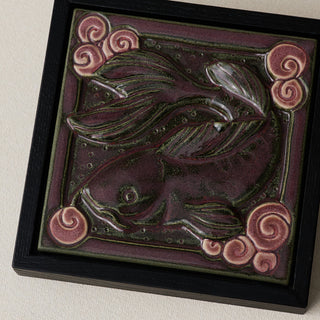 Close-up details of the sculpted tile, with visible carvings and layered glaze.