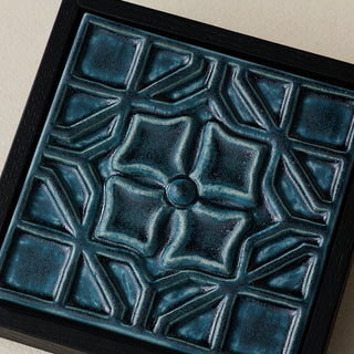 Close-up details of the sculpted tile, with visible carvings and layered glaze.