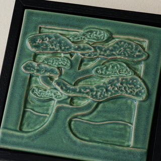 Close-up details of the sculpted tile, with visible carvings and layered glaze.