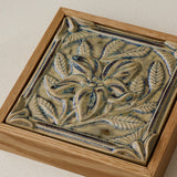 Close-up details of the sculpted tile, with visible carvings and layered glaze.
