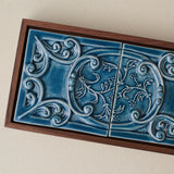 Close-up details of the sculpted tile, with visible carvings and layered glaze.