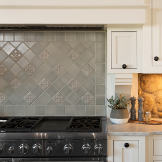 Kitchen with tiled backsplash, stove, and decorative elements.